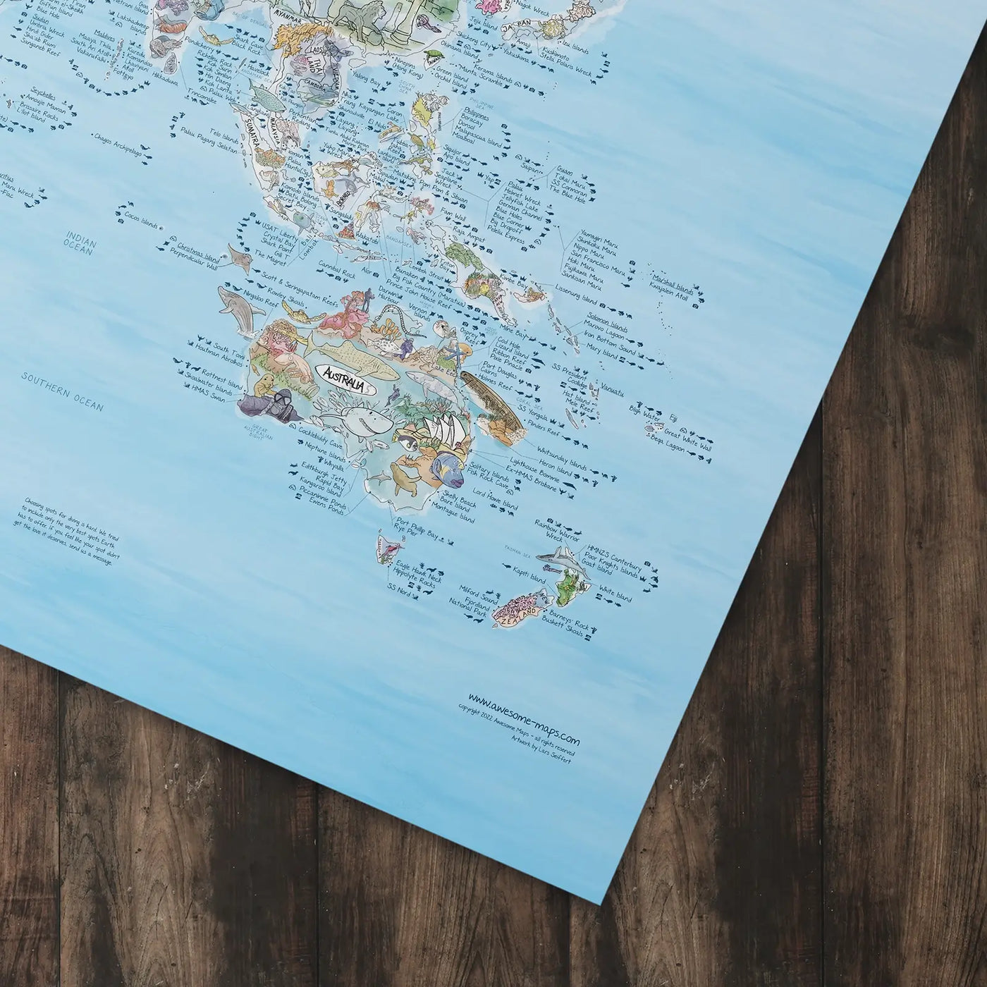 Bottom right corner of the Dive Map poster of the world lying flat on a table