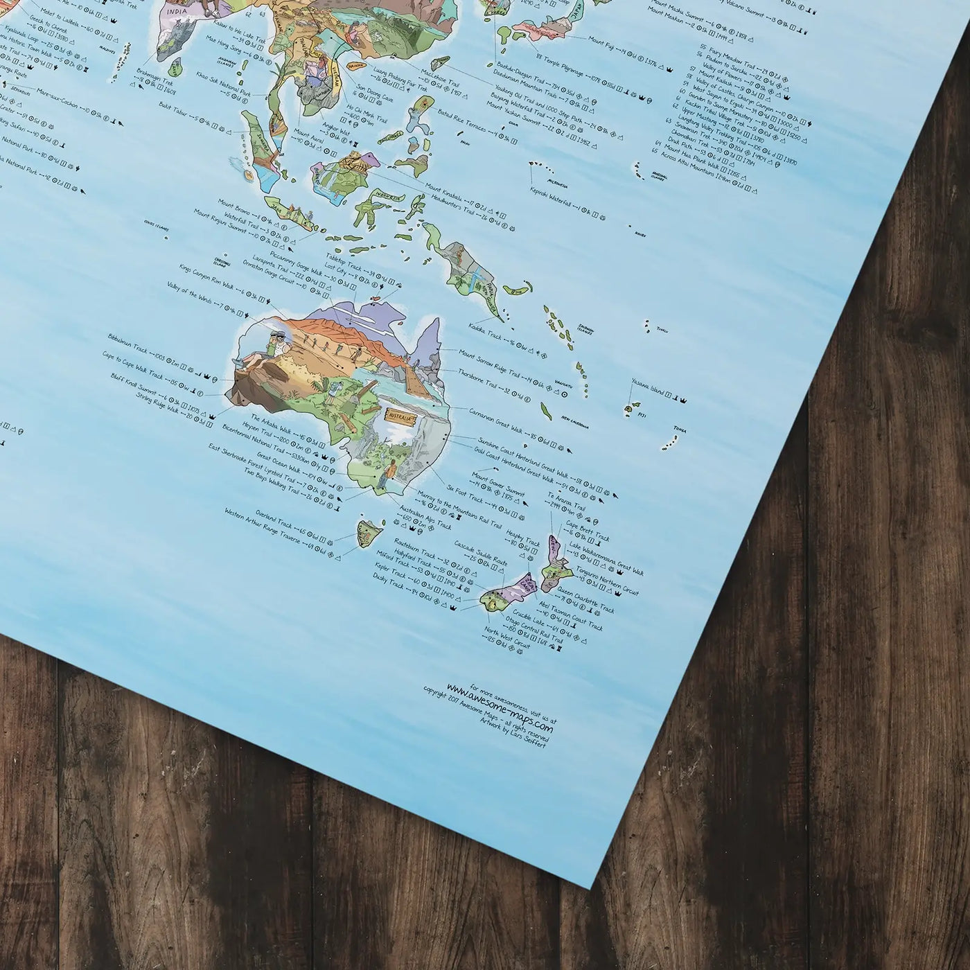 Bottom right corner of the Hiking Map poster of the world lying flat on a table