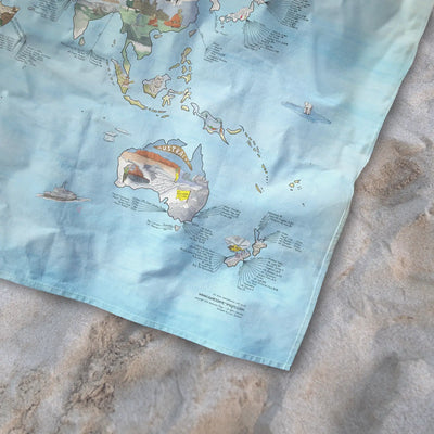 Bottom right corner of the Snowtrip Map towel of the world lying on the sand