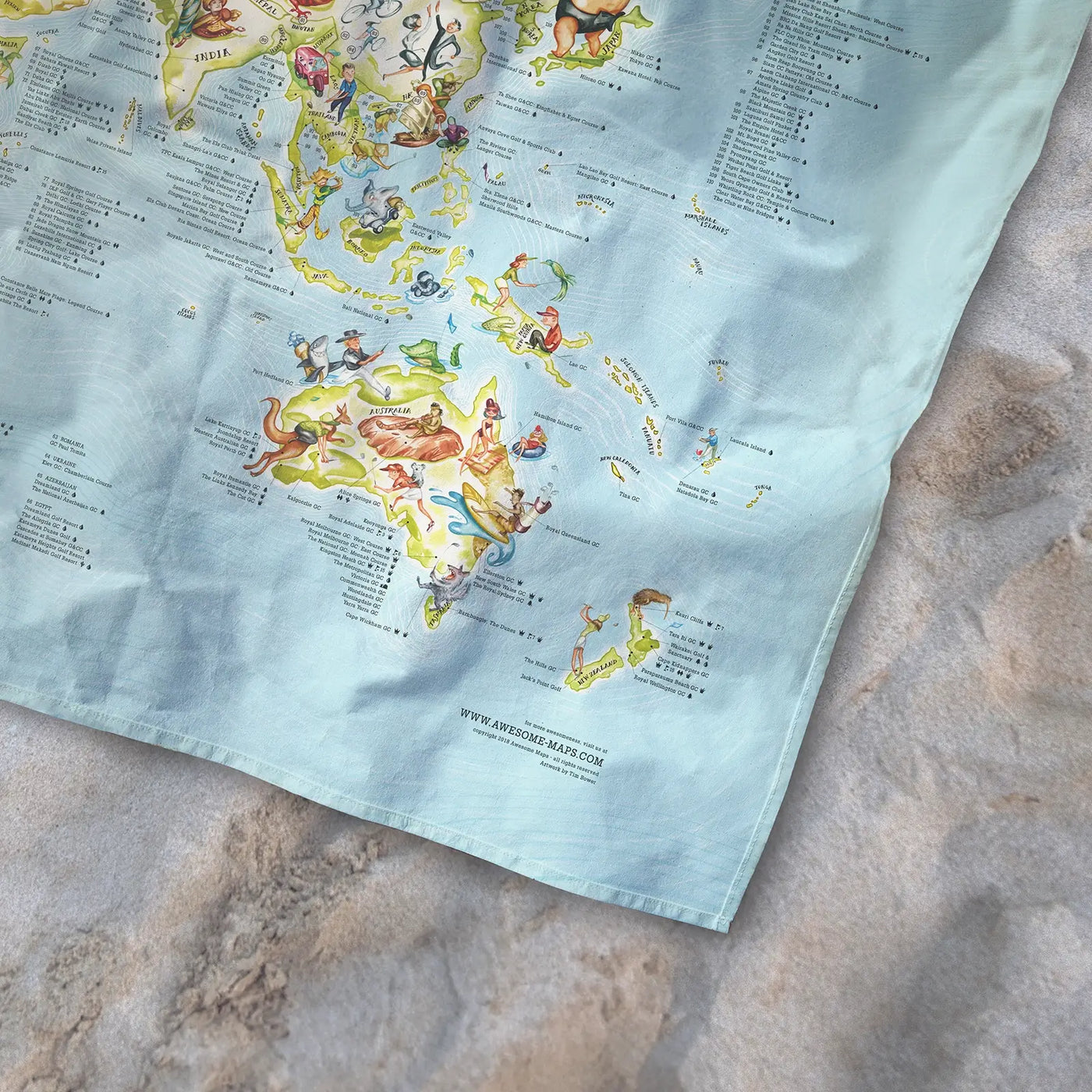 Bottom right corner of the Golf Map towel of the world lying on the sand