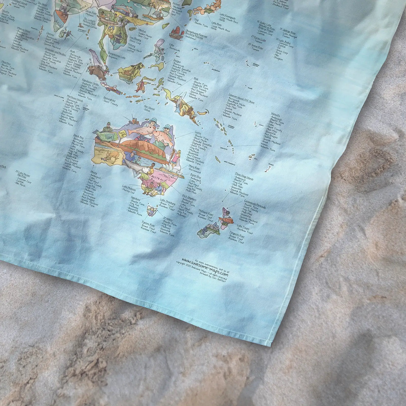 Bottom right corner of the Fishing Map towel of the world lying on the sand