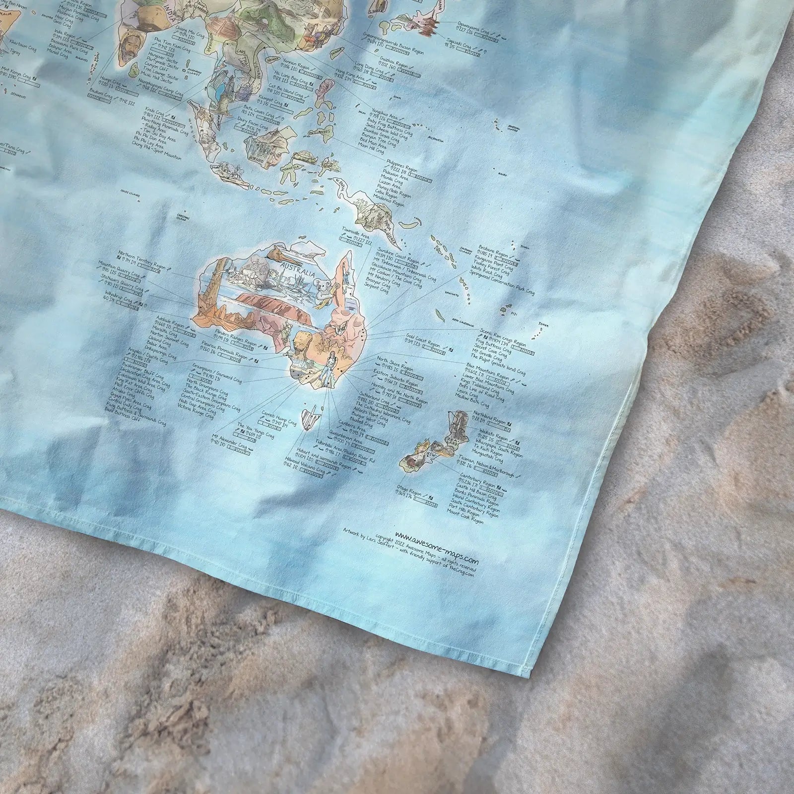 Bottom right corner of the Climbing Map towel of the world lying on the sand