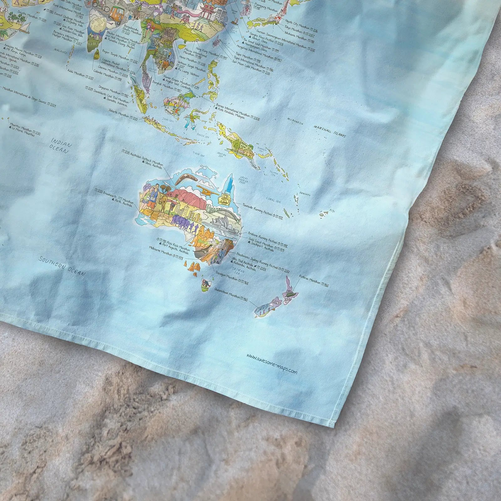 Bottom right corner of the Running Map towel of the world lying on the sand