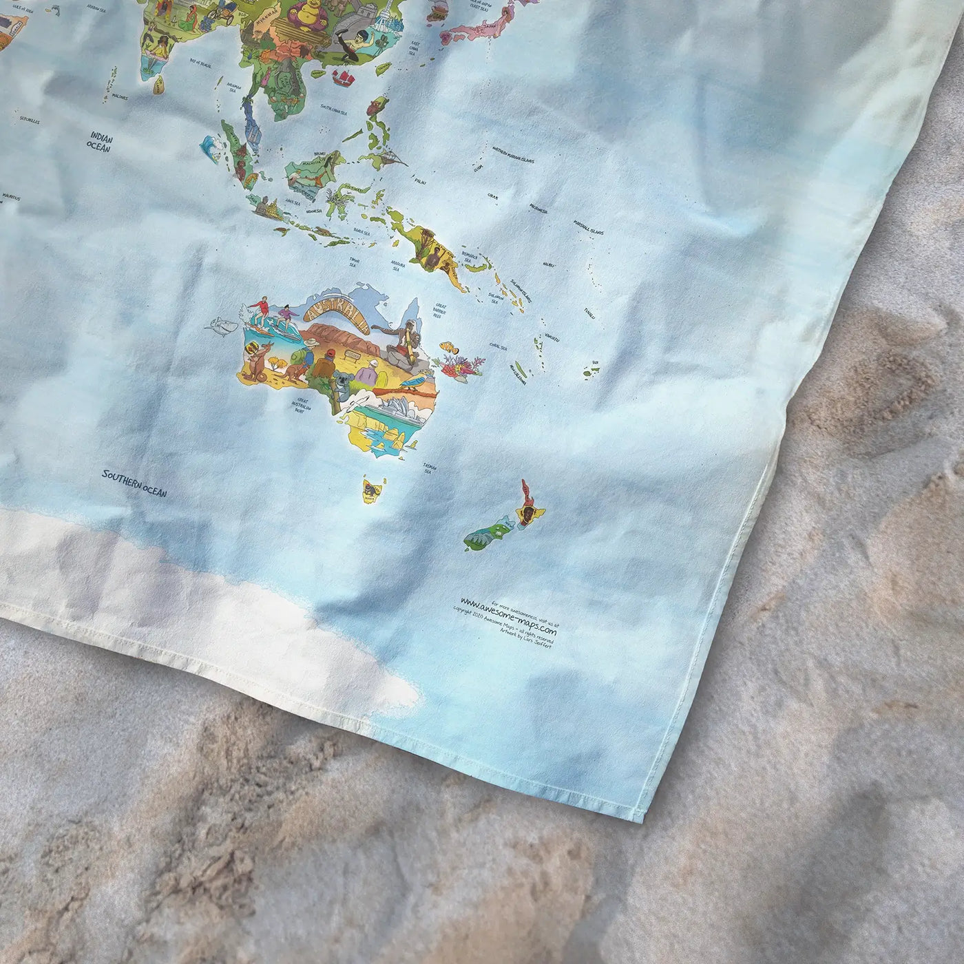 Bottom right corner of the Little Explorers Map towel of the world lying on the sand