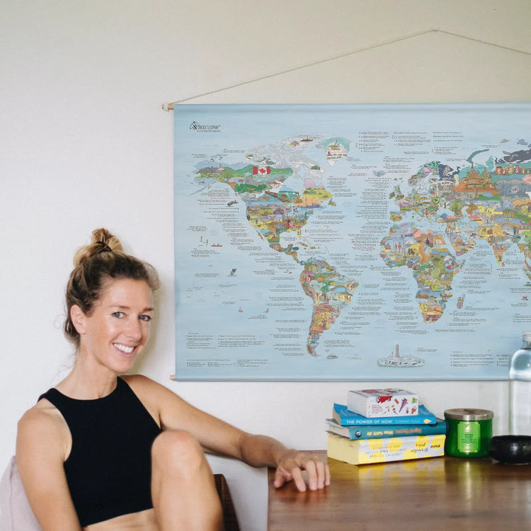 Someone sitting in front of the Bucketlist Map roll down canvas hanging on the wall