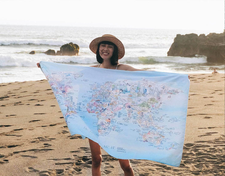 Someone holding the Dive Map towel at the beach