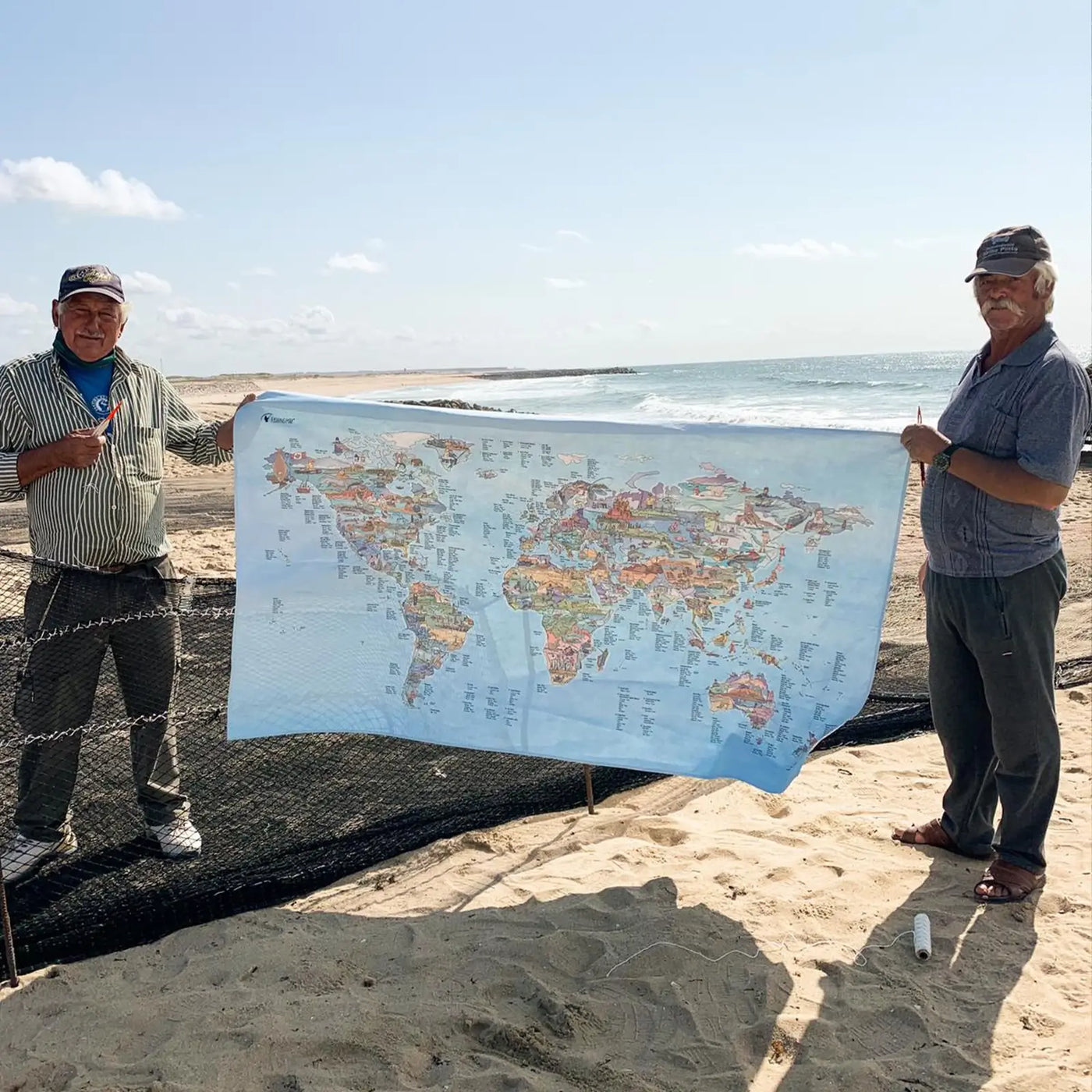 Two fishermen holding the Fishing Map towel at the beach