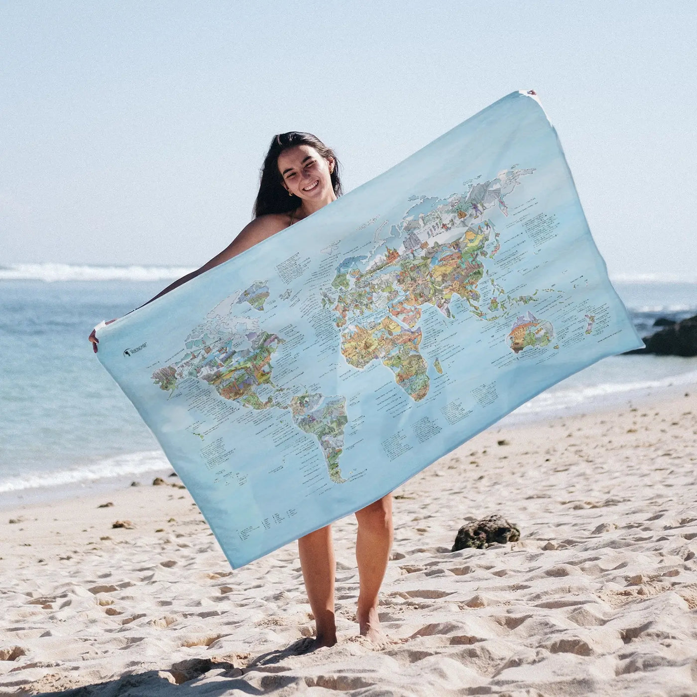 Someone holding the Hiking Map towel at the beach