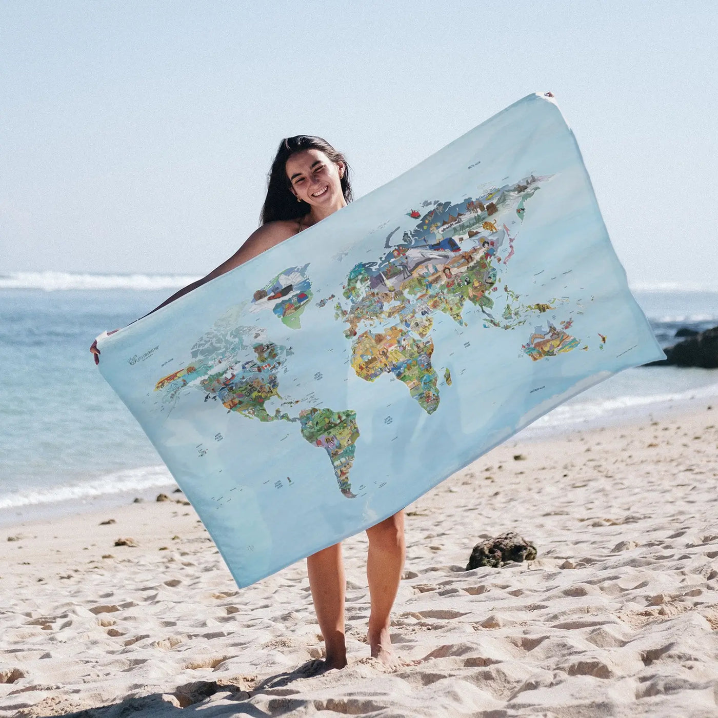 Someone holding the Little Explorers Map towel at the beach