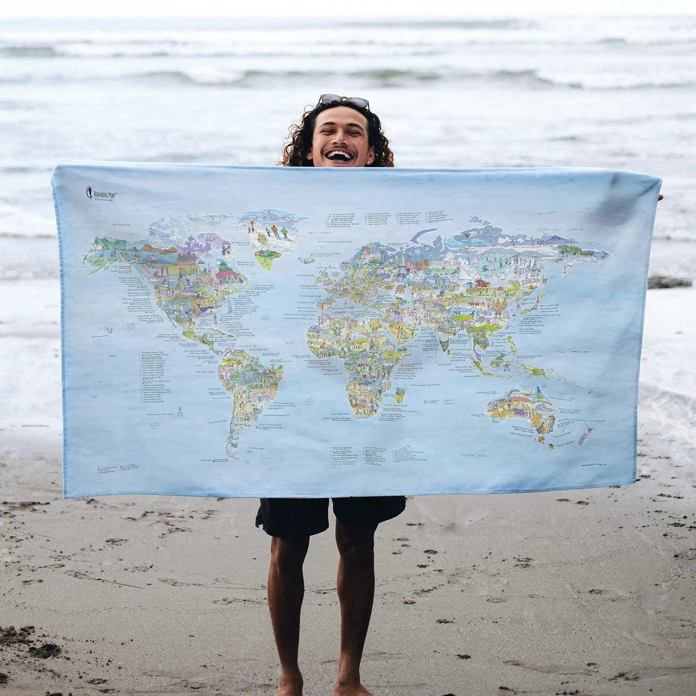 Someone holding the Running Map towel at the beach