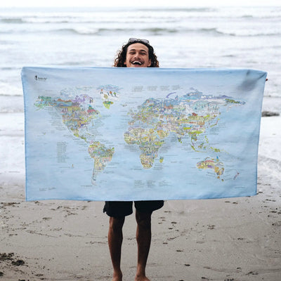 Someone holding the Running Map towel at the beach