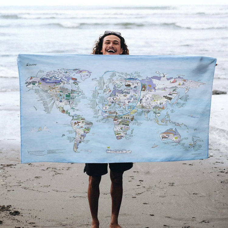 Someone holding the Snowtrip Map towel at the beach