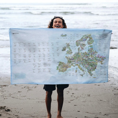 Someone holding the Road Trip Map towel at the beach