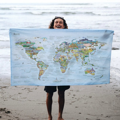 Someone holding the Bucketlist Map towel at the beach