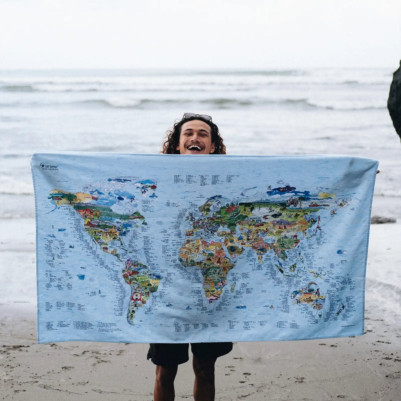 Someone holding the Surftrip Map towel at the beach